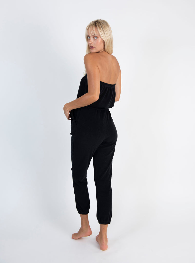 LVHR Camilla Jumpsuit in black made from super soft organic recycled terry cloth knit with front pockets and tie sash belt. Elastic cuffs, waist and neckline. Back.